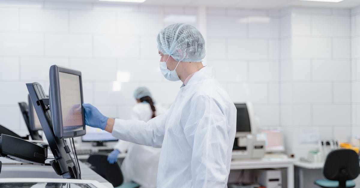 Scientist wearing protective gear while interacting with lab equipment and screen.